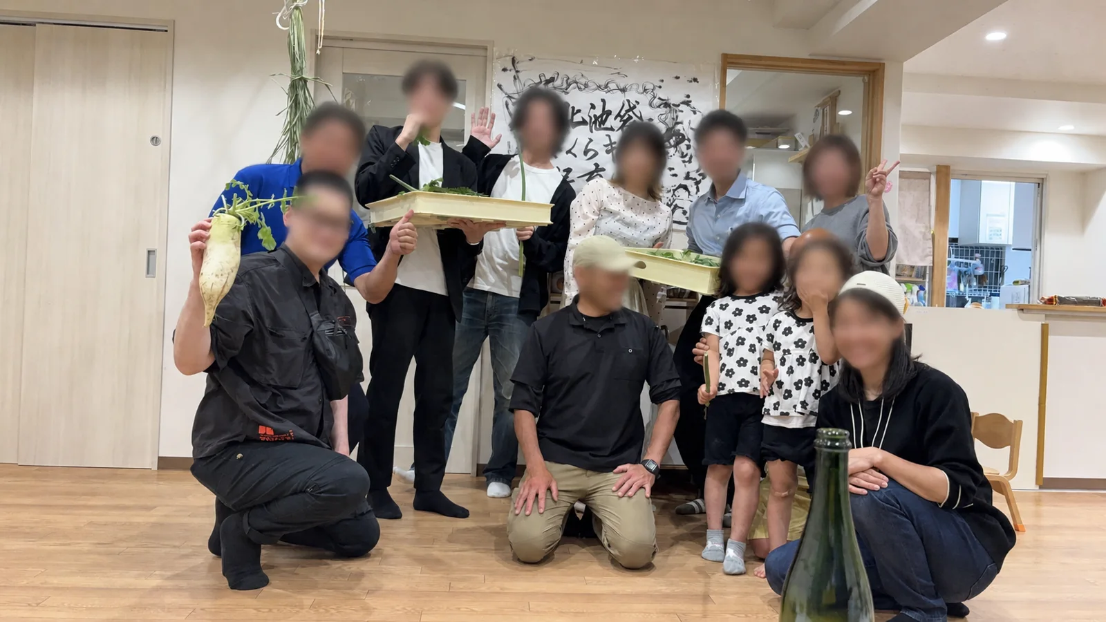 野菜を手に集まった交流会の参加者たち。顔にはぼかし処理を施しています。